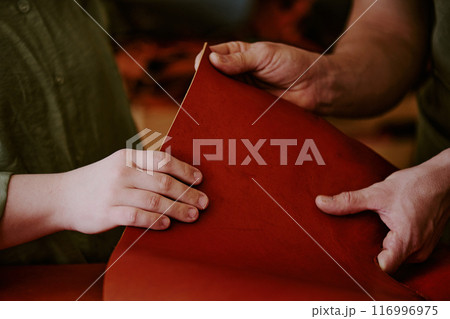 Medium close up of unrecognizable female and male hands touching chocolate colored leather piece Medium close up of unrecognizable female and male hands touching chocolate colored leather piece 116996975