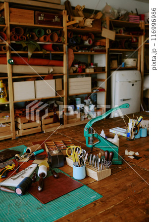 Old work table with punch machine workpieces and extra tools on top, huge number of fabric rolls on shelves in background Old work table with punch machine workpieces and extra tools on top, huge number of fabric rolls on shelves in background 116996986