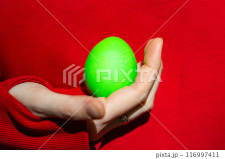 Enigmatic Figure Grasping a Vibrant Green Easter Egg 116997411