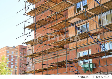 A brick house under construction with wooden scaffolding 116997602