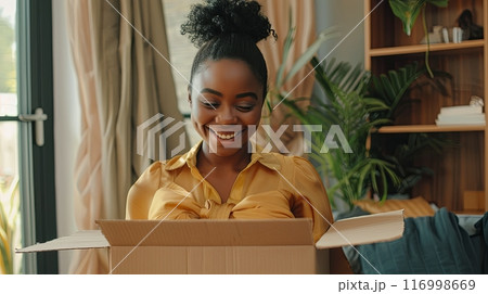 A happy young woman opening a box with a delighted expression 116998669