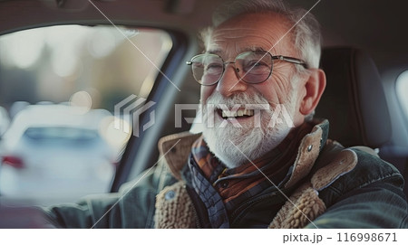 A joyful elderly man with glasses and a white beard, smiling while sitting in a car 116998671
