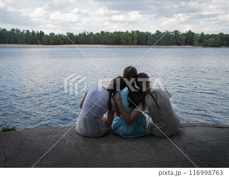 Three girls sitting at the river 116998763