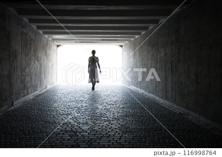 A woman emerges from a tunnel into the light 116998764