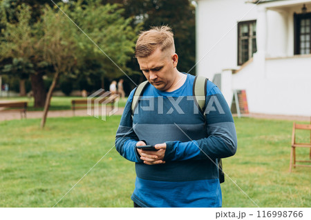 Sad young man receives bad news on the phone outdoors. 30s man using smartphone with serious expression in the park. Negative people emotion 116998766