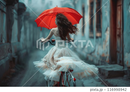 girl in a dress rides a bicycle with an umbrella 116998942