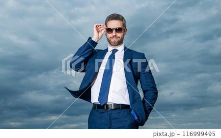 Professional man sky background. Grizzled man adjusting sunglasses. Happy man in suit outdoors 116999495