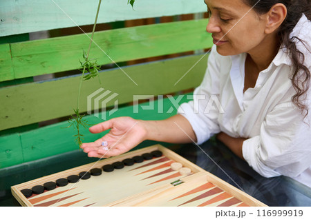 Woman playing backgammon outdoors enjoying a casual game in a relaxed environment 116999919