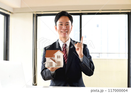 住宅模型を持つスーツ姿の男性会社員 住宅模型を持つスーツ姿の男性会社員 117000004