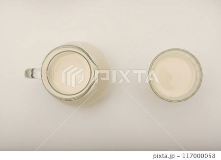 Melted milk in a milk jug and in a glass on a white background. Milk in a bowl. 117000058