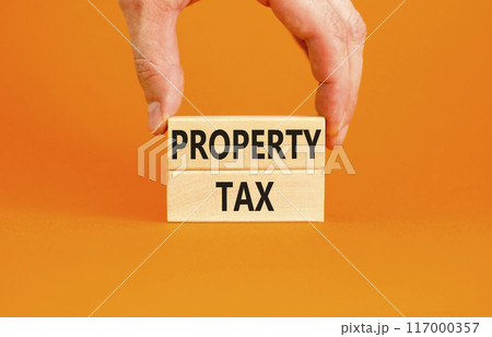 Property tax symbol. Concept words Property tax on wooden blocks. Beautiful orange table orange background. Businessman hand. Business and property tax concept. Copy space. 117000357