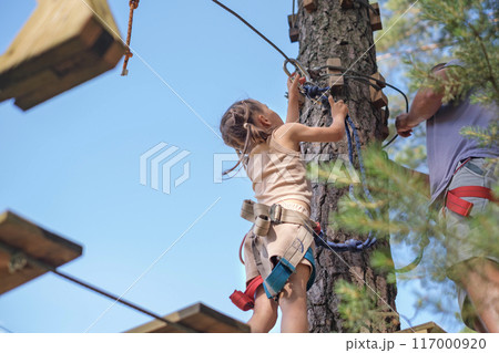 The child adjusts the safety carabiner to pass the rope route at height The child adjusts the safety carabiner to pass the rope route at height 117000920