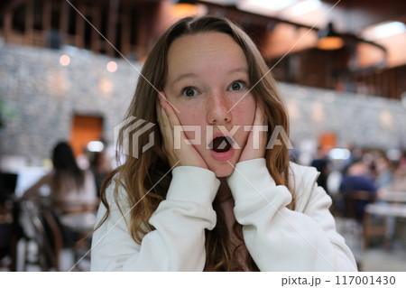 Beautiful woman holding shopping basket full of vegetables and groceries in supermarket pointing to empty space aside 117001430