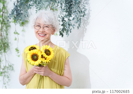 ひまわりの花束を持つ元気なシニア女性 117002685