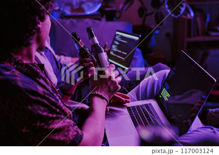 Unrecognizable men celebrating with bottles of beer working code launched on their laptops Unrecognizable men celebrating with bottles of beer working code launched on their laptops 117003124