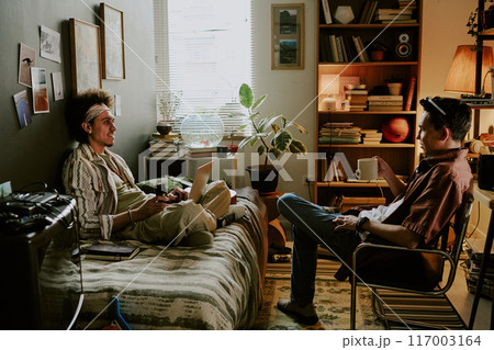 Best friends chilling and having heated conversation during remote work day in dormitory 117003164