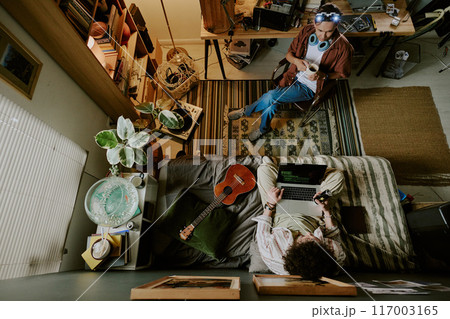 Top view shot of two roomies having break during remote work day, they talking to each other and chilling 117003165