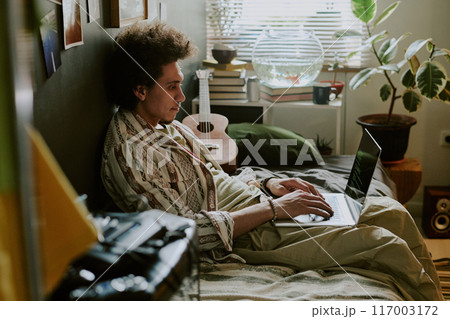 University student writing codes while chilling on soft single bed in his dorm room University student writing codes while chilling on soft single bed in his dorm room 117003172