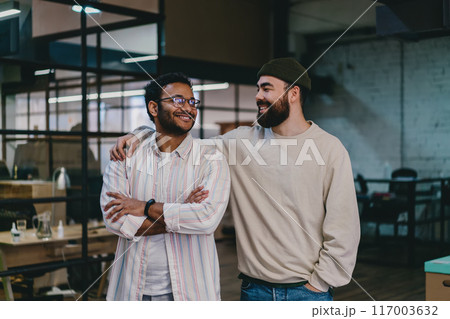 Cheerful multiethnic colleagues standing together in modern office 117003632