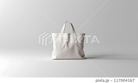 A white tote bag made of natural material rests on a white surface 117004167