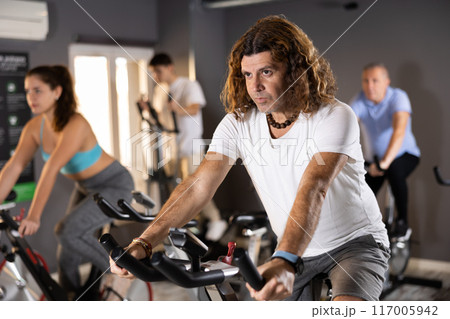 Man doing cardio training on stationary bike in gym Man doing cardio training on stationary bike in gym 117005942
