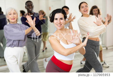 Cheerful young lady learning new modern dance in group dance lesson 117005953