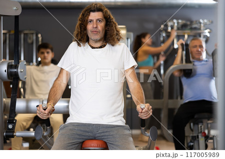 Portrait of athletic man during workout with power exercise machine in modern gym club Portrait of athletic man during workout with power exercise machine in modern gym club 117005989