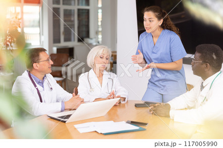 Young female doctor speaks at meeting of colleagues and tells reports on condition of patients Young female doctor speaks at meeting of colleagues and tells reports on condition of patients 117005990