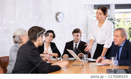 Young woman discussing business project with team in office 117006029
