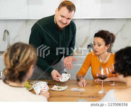 Happy group of friends playing poker cards and drinking wine 117006356