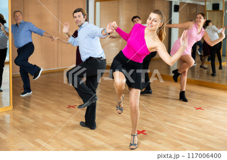 Middle-aged pair practicing Latino dance in dance studio 117006400