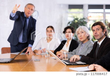 Focused businessman listening to presentation of partners during meeting 117006417