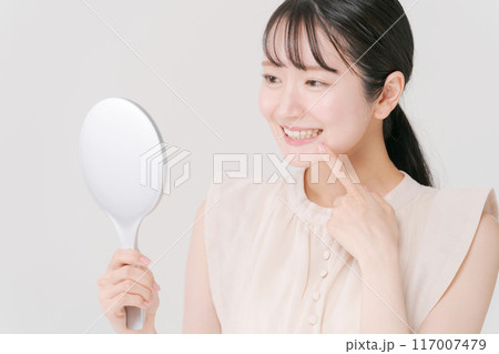 鏡を持ち歯をチェックをする女性 117007479