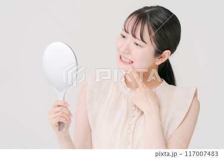 鏡を持ち歯をチェックをする女性 鏡を持ち歯をチェックをする女性 117007483