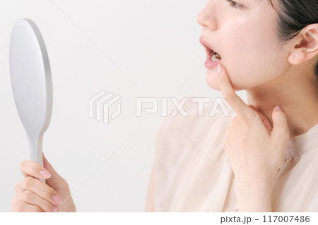 鏡を持ち歯をチェックをする女性 117007486