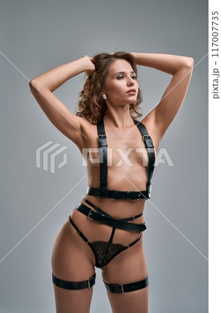 Sexy feisty woman in leather belts with raised arms Sexy feisty woman in leather belts with raised arms 117007735