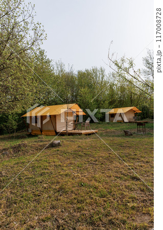 Cozy open glamping tents with light inside in summer camp. Camping tent for holiday and vacation 117008728