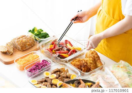 作り置き料理を盛り付けるエプロン姿の女性 作り置き料理を盛り付けるエプロン姿の女性 117010901