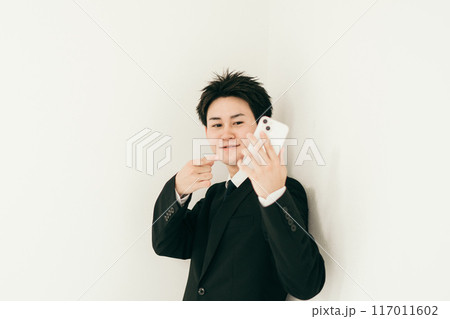 スマホを指さしている20代男性 117011602