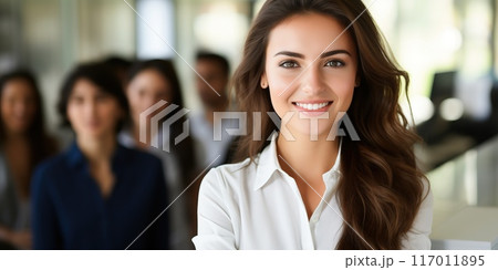 Confident businesswoman smiling with diverse team in background. Concept of leadership, teamwork, and success in a corporate environment. Confident businesswoman smiling with diverse team in background. Concept of leadership, teamwork, and success in a corporate environment. 117011895