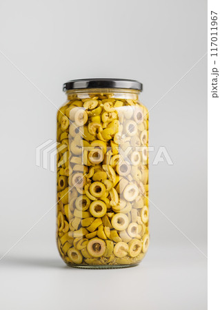 Sliced pickled green olives in brine in jar on gray background. Sliced pickled green olives in brine in jar on gray background. 117011967