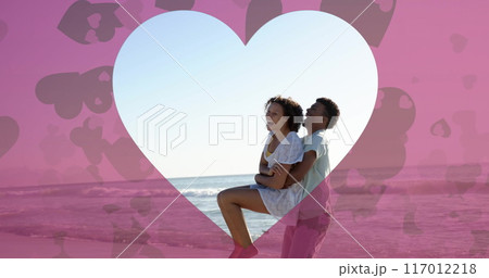 Image of heart cut out over diverse couple in love on beach in summer Image of heart cut out over diverse couple in love on beach in summer 117012218