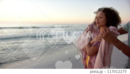 Image of hearts moving over diverse couple in love on beach in summer 117012275