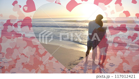 Image of hearts moving over diverse couple in love embracing on beach in summer 117012421
