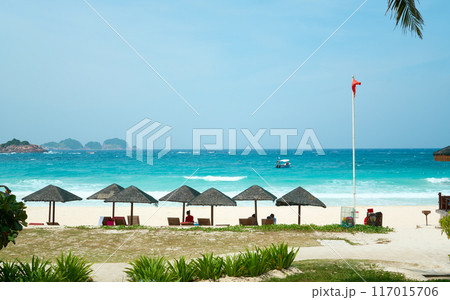 Tourists relaxing under parasols on a tropical beach in malaysia Tourists relaxing under parasols on a tropical beach in malaysia 117015706