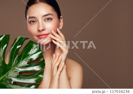 Close up woman face with green exotic leaf Close up woman face with green exotic leaf 117016236