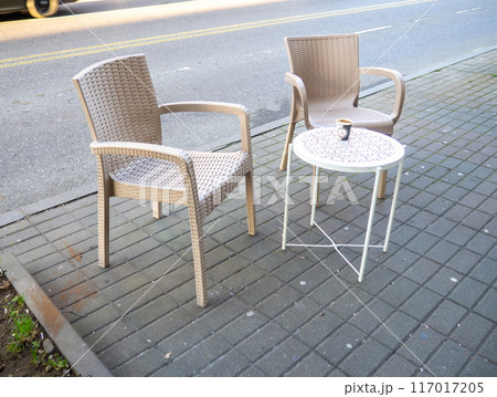 Empty table with two chairs in a street cafe. Free space at the diner. The coffee is cold on the table. Empty table with two chairs in a street cafe. Free space at the diner. The coffee is cold on the table. 117017205