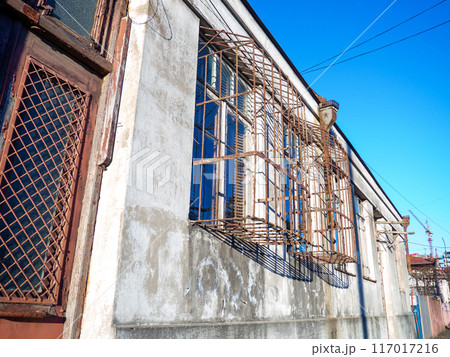 Window with an unusual lattice. An old house. Shabby walls of the house. Batumi architecture. Protection from thieves. Window with an unusual lattice. An old house. Shabby walls of the house. Batumi architecture. Protection from thieves. 117017216
