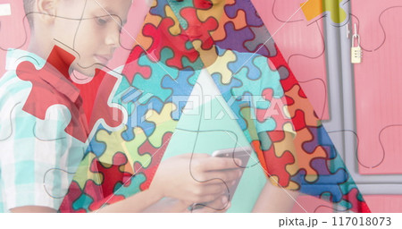 Jigsaw puzzle and ribbon icon against two diverse boys using smartphone at school Jigsaw puzzle and ribbon icon against two diverse boys using smartphone at school 117018073