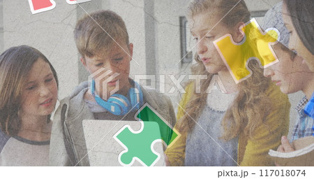 Jigsaw puzzle and human head icon over diverse group of students using laptop at school 117018074